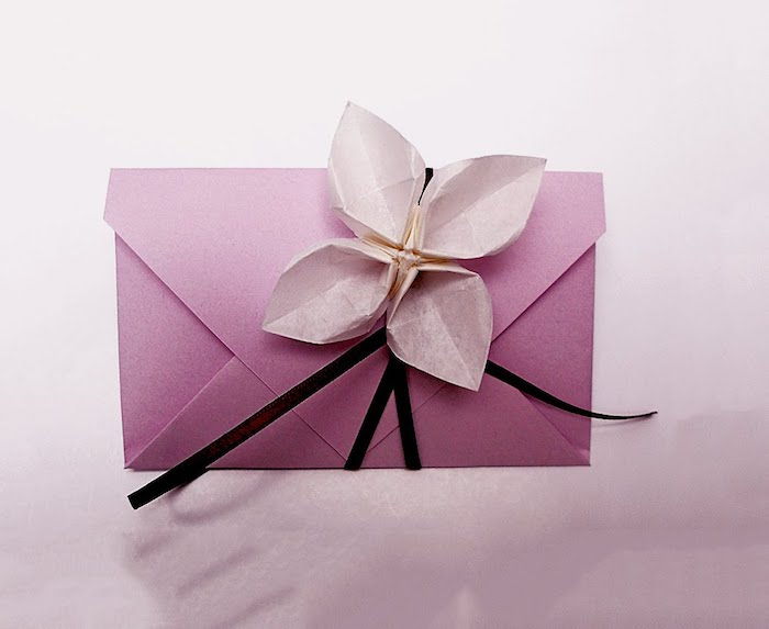 Å lage konvolutter - en vakker origami blomst som et ornament av konvolutt i rosa farge