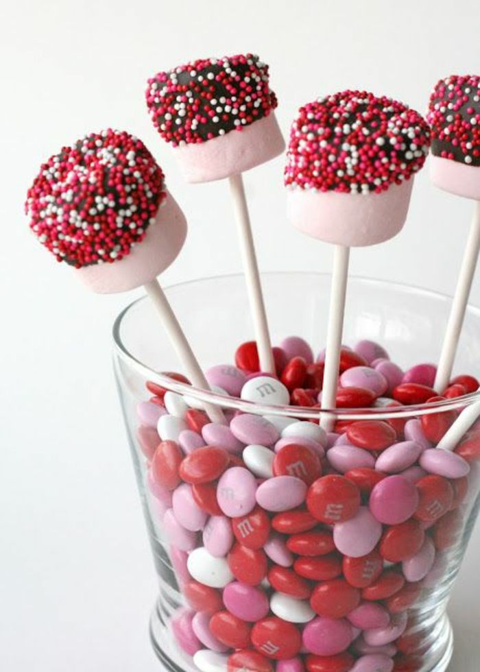 un vas de sticlă cu dulciuri, un tort pe un baston cu ciocolată și perle de zahăr