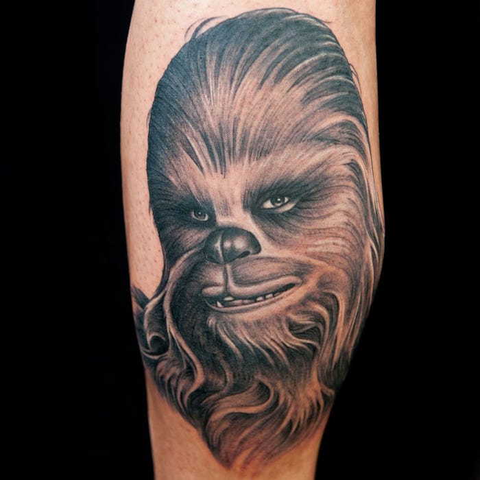 un picior cu un tatuaj de război stele, cu o chewbacca mare brună, cu un nas negru și ochi verzi