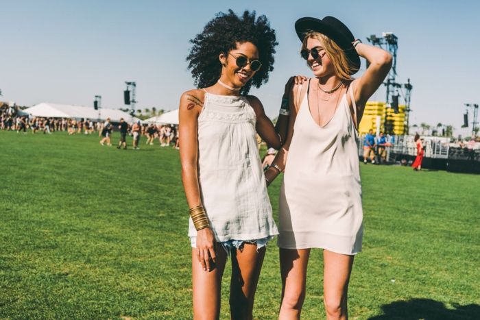 hippie festival outfits Två vackra kvinnor har kul på det gröna fältet som lyssnar på musik och njuter
