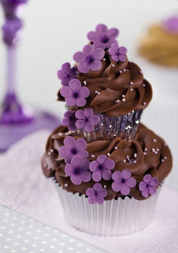 čokoládový košíček so šľahačkou a fialovými kvetmi zdobia