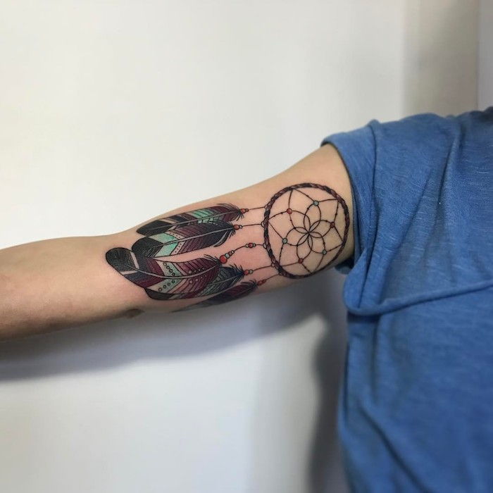 Idea per un tatuaggio sulla mano con un tatuaggio con un acchiappasogni nero con belle piume lunghe, nere e verdi