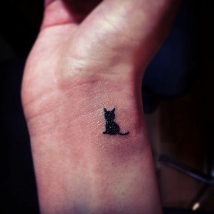 idee pentru un tatuaj cu pisica neagra pe incheietura mainii - aici este o pisica cu un cocos negru