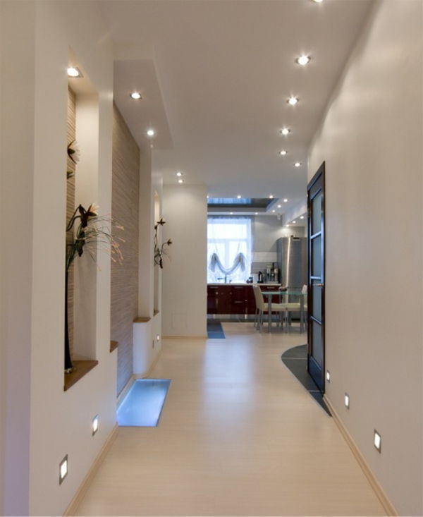 Taklampor-väggbelysning-i-vit-korridor med dekorativa växter