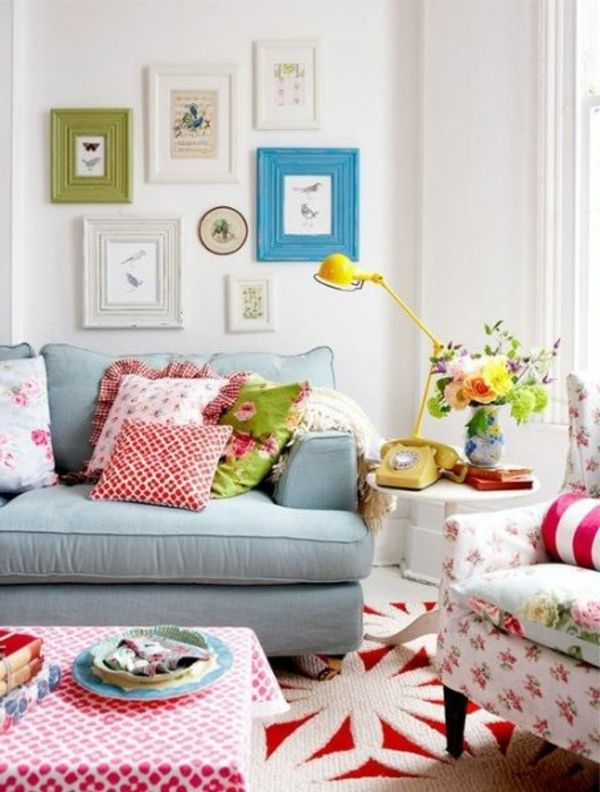 Obývacia izba s vankúšmi, obrázky s farebnými rámami na stenu a žltou lampou