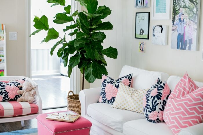 Vardagsrumsinredning med rosa kuddar med blommotiv för vit soffan