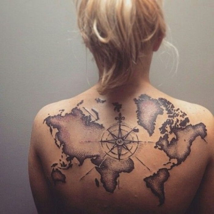 črni kompas in zemljevid sveta - ideja za sodobno tetovažo na hrbtu mlade ženske