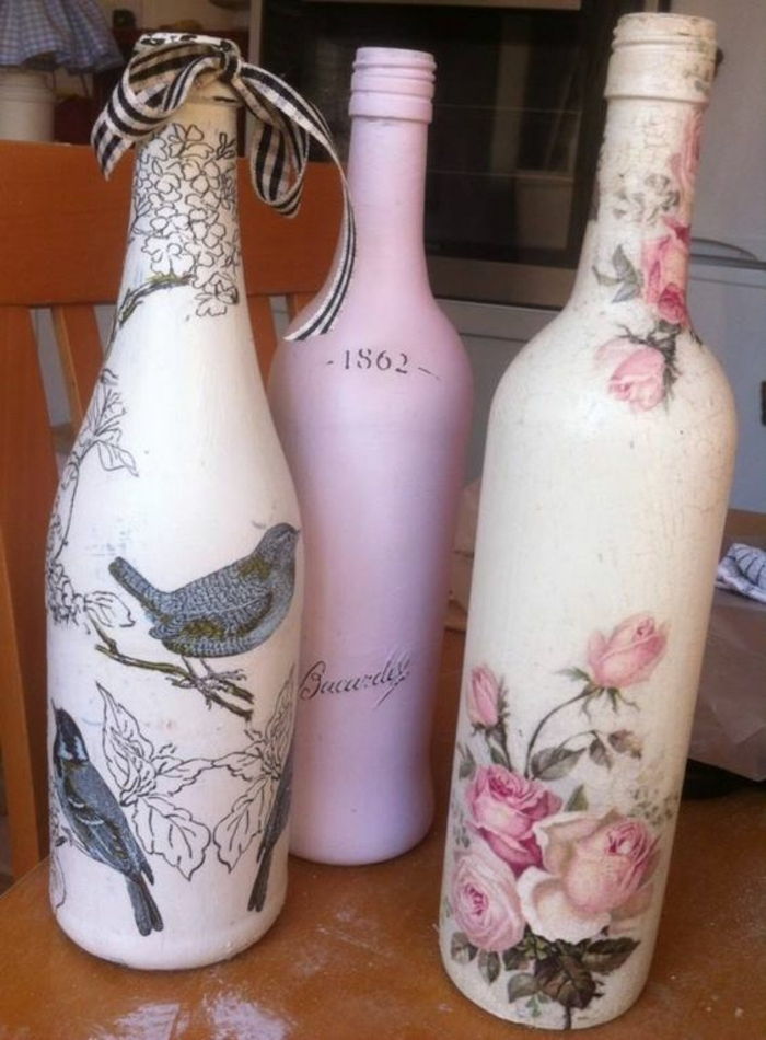 drie flessen met servetten met roze bloemen en grijze vogels en een grijze mus
