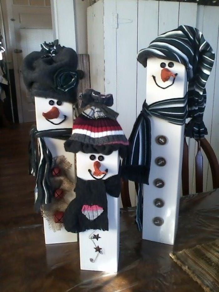 beli snežaki iz lesa s črnimi klobuki s črno rožo, s črnimi očmi in pomarančami nas nosijo sklede s srcem