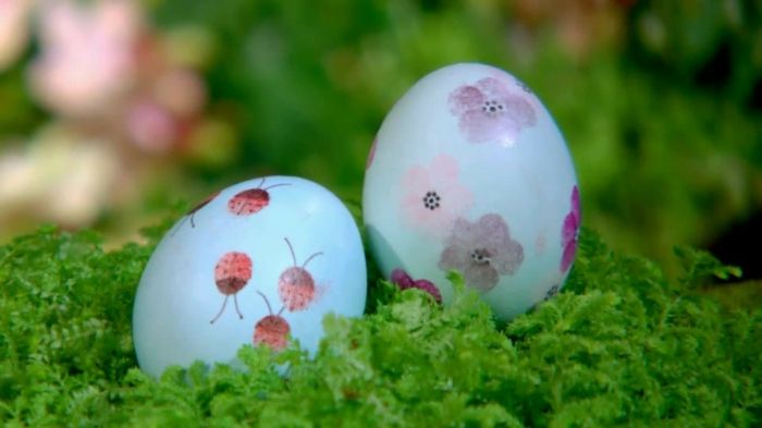 dwa zabawne jajka w trawie - jedna z biedronką, druga z kwiatami