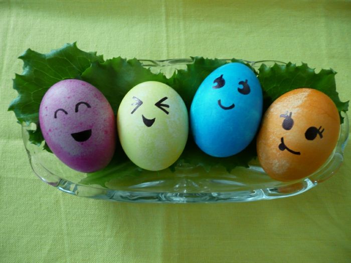 Ovos de Páscoa enfrenta em quatro cores diferentes em um copo com folhas