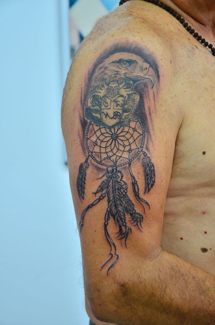 Qui vi mostriamo un tatuaggio con un'aquila e un acchiappasogni nero con lunghe penne sulla spalla