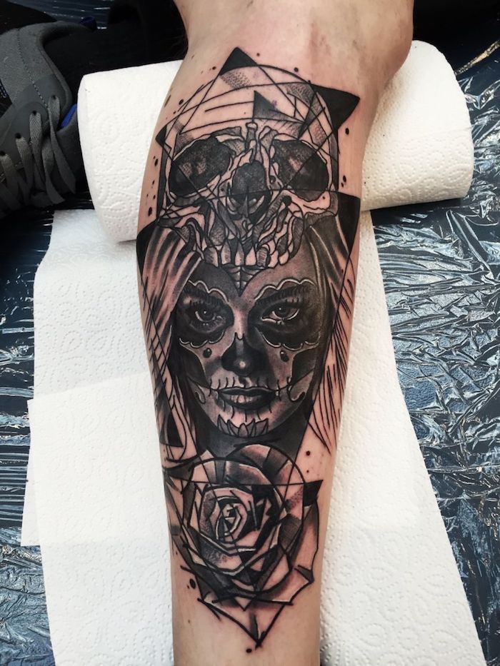 un grande tatuaggio nero con un grande cranio bianco, una giovane donna e una rosa - che significa la catrina