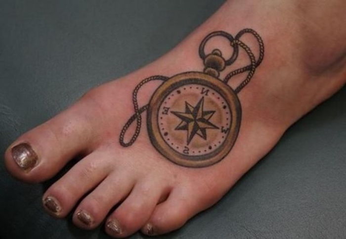 Tukaj je ideja za tetovažo na nogi - nogo z lakom za nohte in tetovažo z zlatim kompasom