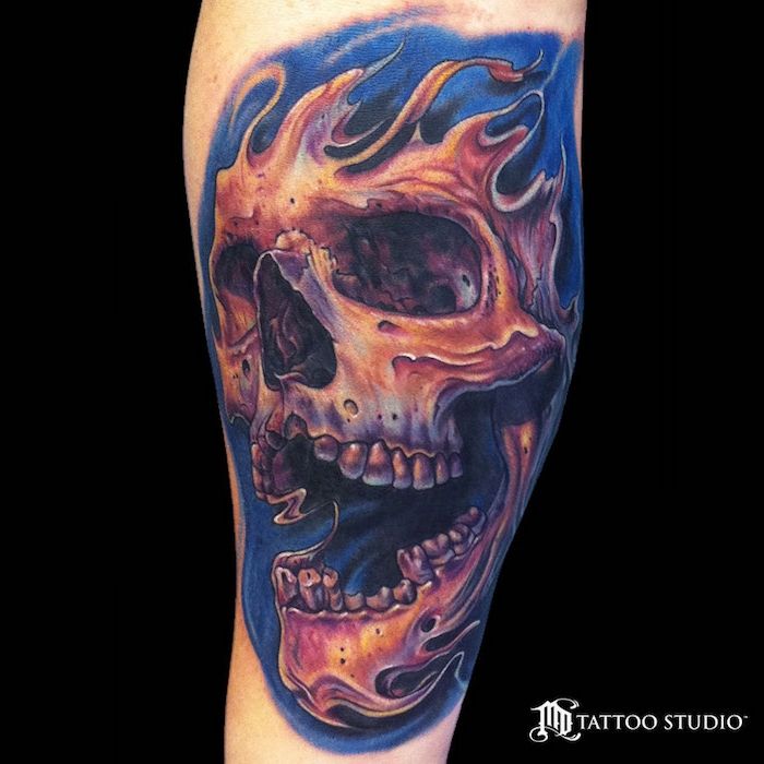 En tatovering med en stor oransje brennende skalle og brannbøtte med tatovering