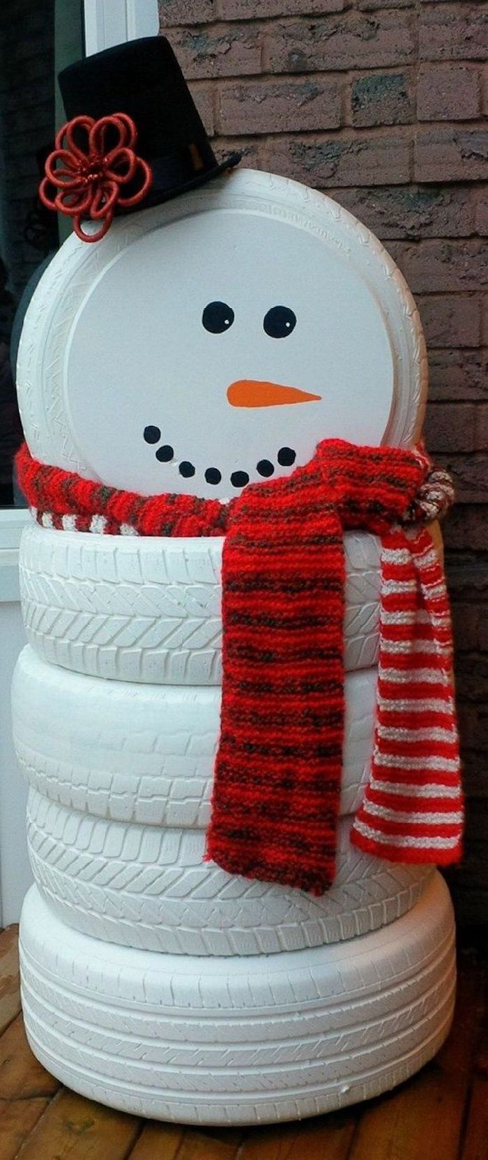 veľký snehuliak s červeným šálom, čierny klobúk a oranžový nos - snehuliak z bielej pneumatiky