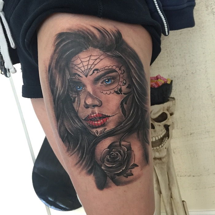 Been met een La Catrina-tatoeage met een jonge vrouw met rode lippen en blauwe ogen en een zwart spinneweb