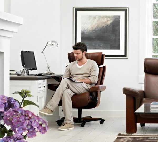 vienas žmogus-darbas-ir-sėdi ant-stressless-biuro kėdė-didelis vaizdas už jo