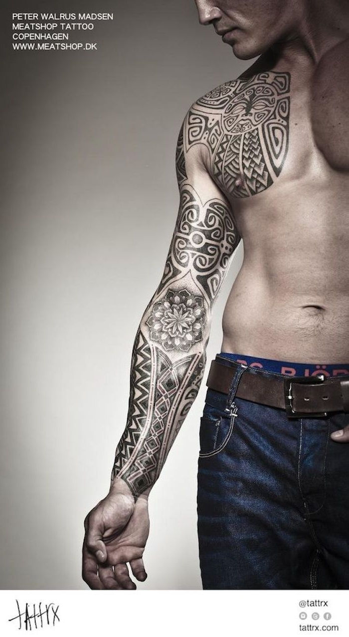 significato tatuaggio maori - un giovane uomo con pantaloni blu e una mano che tiene un grande tatuaggio nero maorie con motivi di maori tatttoo neri