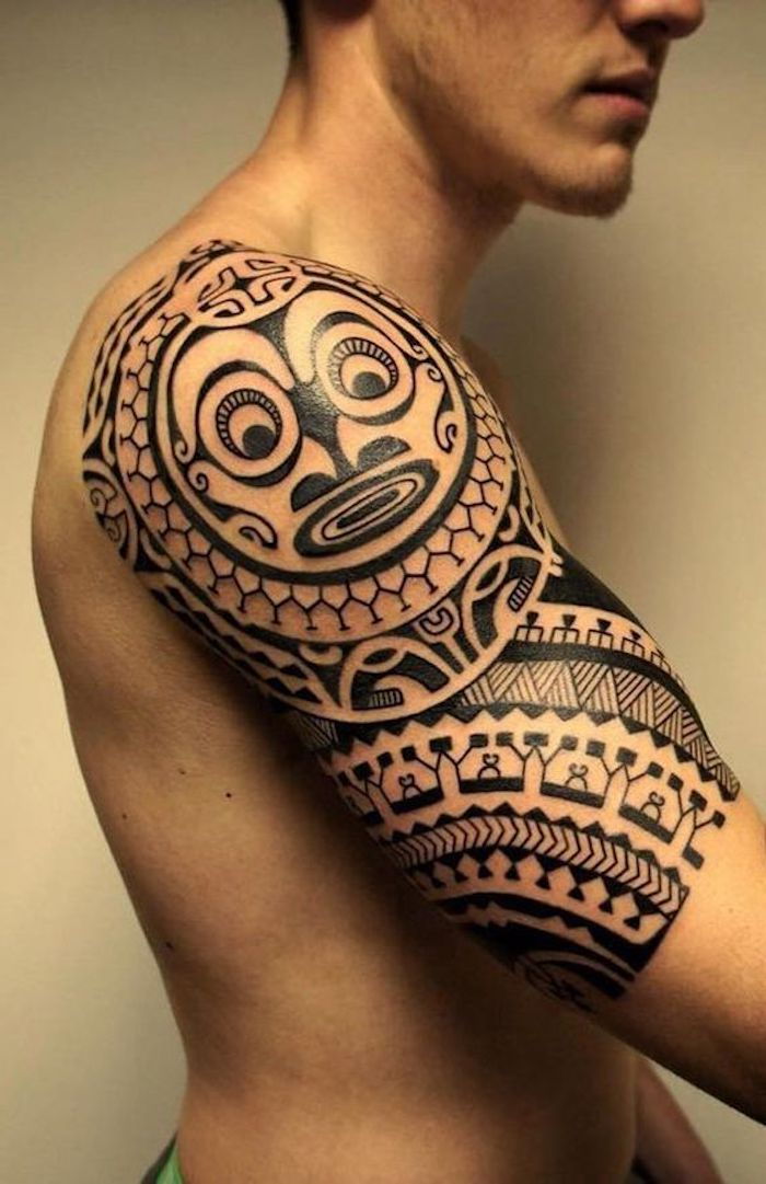 Maori tattoo pomen - moški z roko, ki ima velik črni maorie tatoo z bitje s črnim nosom in dve veliki črni oči