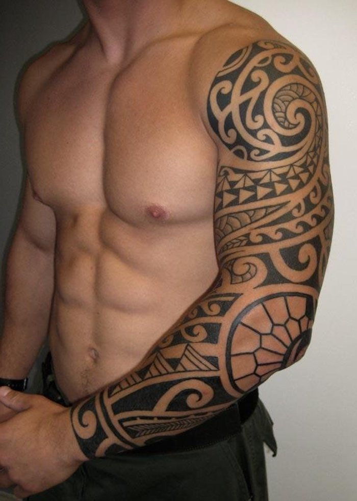 un uomo con una mano che tiene un grande tatuaggio nero con motivi del tatuaggio maori