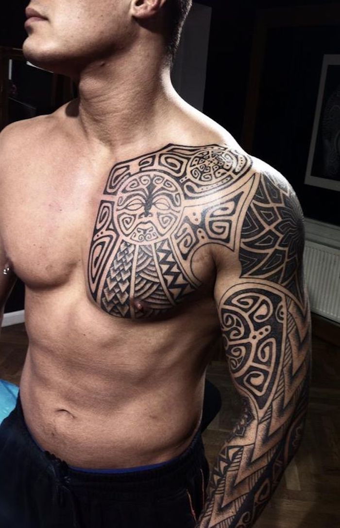 Un giovane con una mano che regge un grande tatuaggio Maori nero e un piccolo mostro nero con gli occhi bianchi