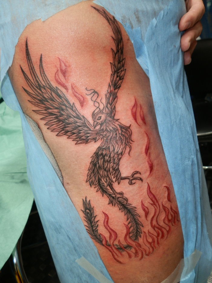 man med en stor svart tatuering med en svart flygande Phoenix med svarta fjädrar och eldfenix från askens tatuering
