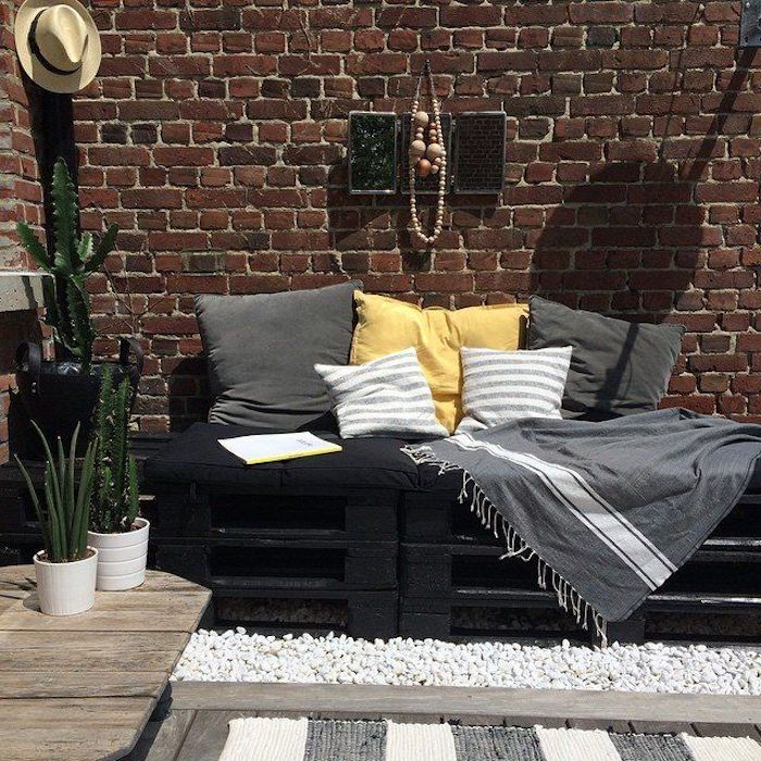 Şimdi, yeşil bitkiler ile gri ve sarı yastıklar ve şapka ve saksıları olan siyah bir kanepe için harika bir fikir sunuyoruz.
