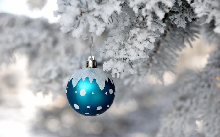 en liten blå julkule og et tre med snø - et romantisk vinterbilde
