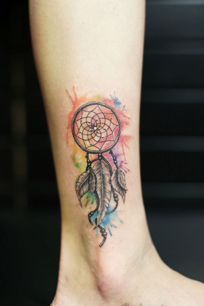 Kitas akvarelės tatuiruotės idėja su spalvinga gražia maža maža svajonių gaudikliu su kojomis ant jo kojos