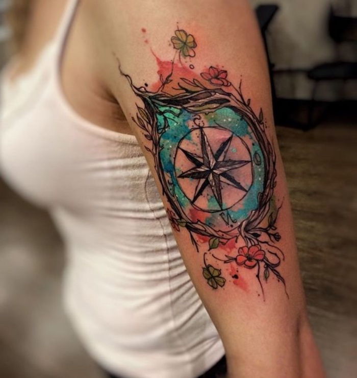 Tukaj boste našli mlado ženo s pravljico, veliko in lepo tetovažo s črnim, velikim kompasom z dvema rdečima rožama in dvema zelenima cvetjema