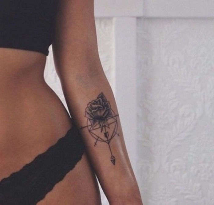 Aici vă arătăm o tânără femeie cu un tatuaj negru și un tatuaj cu busola mică - o femeie cu un tatuaj