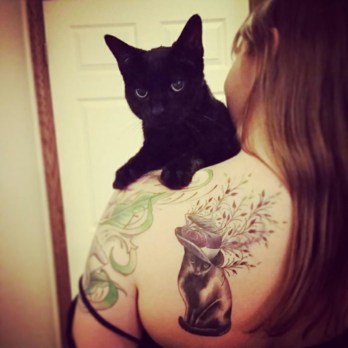 Aici puteti gasi nch o idee pentru un tatuaj pisica - aici este o pisică neagră și o femeie cu un tatuaj pe umăr, cu o pisică neagră, pălărie și plante