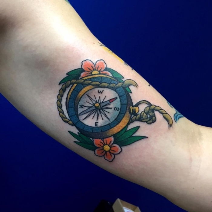 Oto pomysł na tatuaż z małym kompasem z dwoma czerwonymi kwiatami i małymi zielonymi liśćmi - bajecznym tatuażem na dłoni