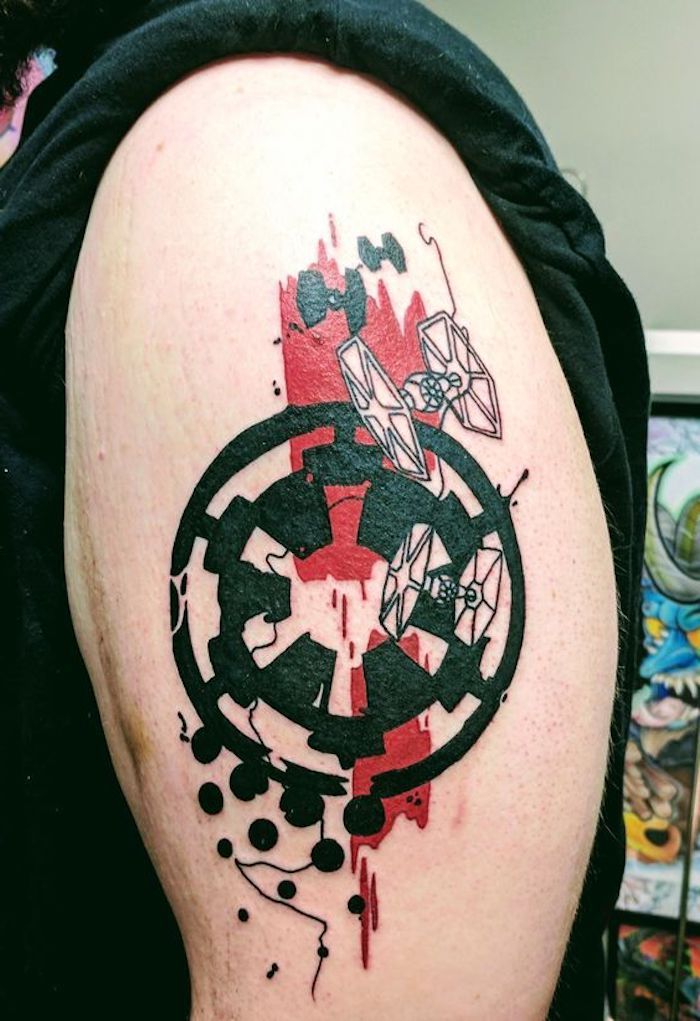 om cu o mână care deține un tatuaj de război cu stele mari, cu un logo de război cu stele negre și două nave spațiale mici