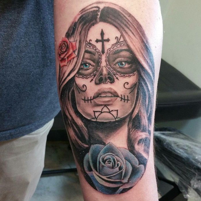 Hand met een zwarte tatoeage met een rode roos en een grote rode roos en een jonge vrouw met groene ogen en een zwart kruis