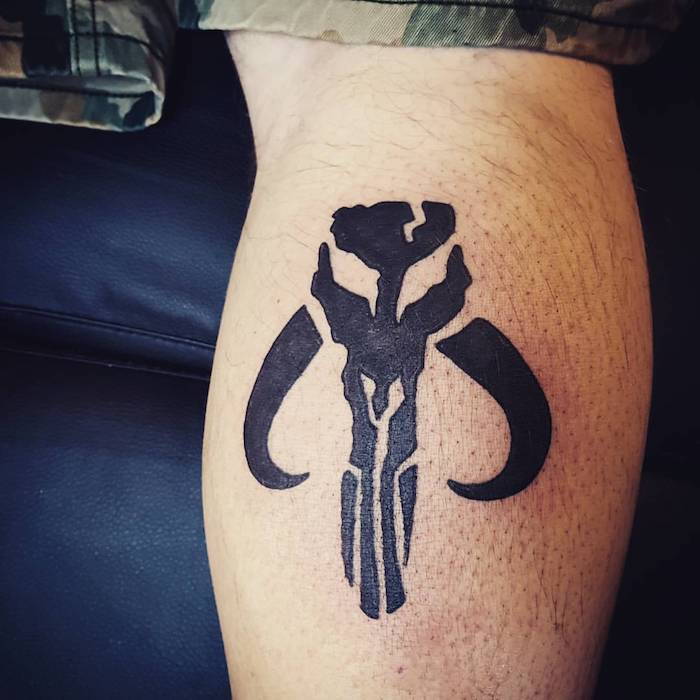 un bărbat cu o mână care deține un tatuaj războinic cu stele negre, cu războaie de stele negre fiind
