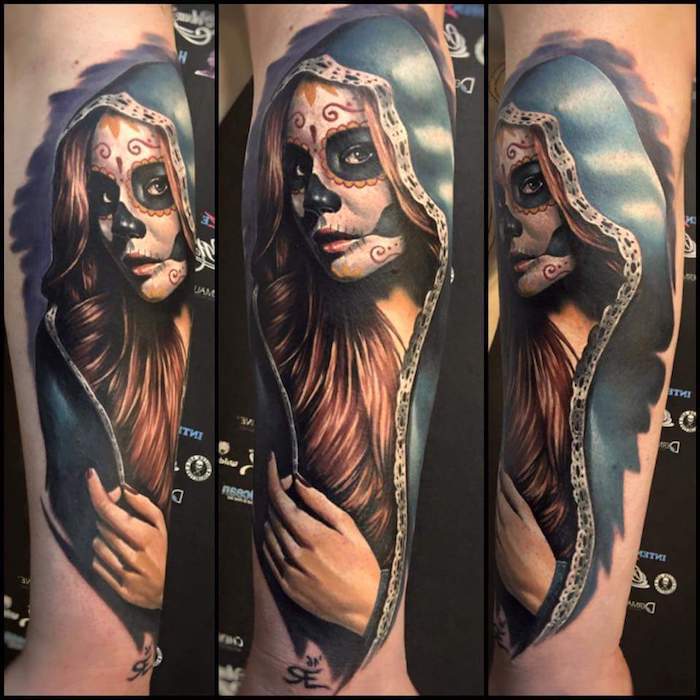 Hand met een grote tatoeage La Catrina met een jonge overleden vrouw met zwarte ogen en een zwarte neus en een rode nagellak