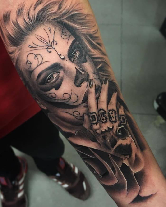 Hand met een grote zwarte tatoeage met een zwarte roos en met een jonge vrouw met een zwarte neus en zwarte ogen en een zwarte nagellak