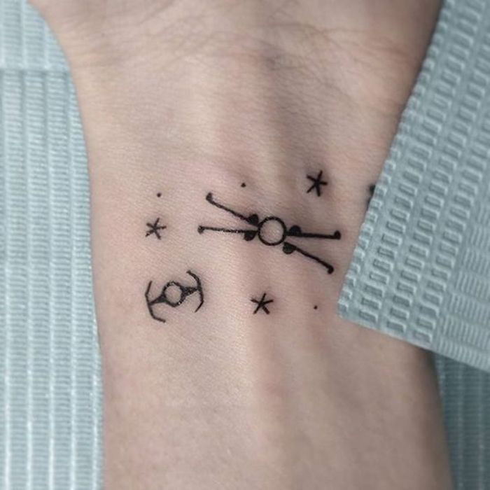 idee pentru un tatuaj de război stele pe încheietura mâinii - un tatuaj negru puțin, cu stele și planete negre și planete și nave spațiale mici