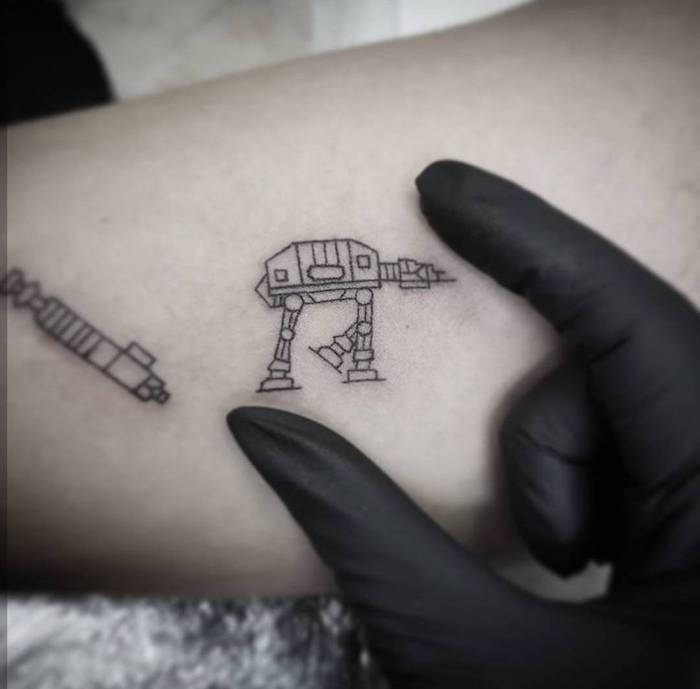 o mână și un mic tatuaj de război cu stele negre, cu un mic robot alb și o mică lumină albă