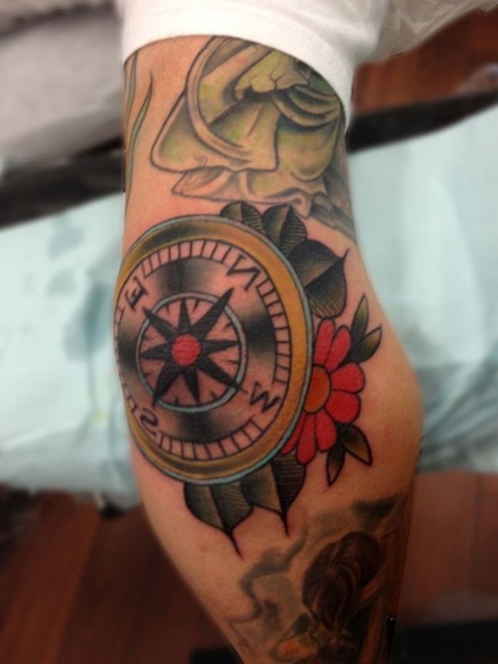kompas z rdečo rožo in zelenimi piščali - ideja za pravljični tattoo kompas na roki
