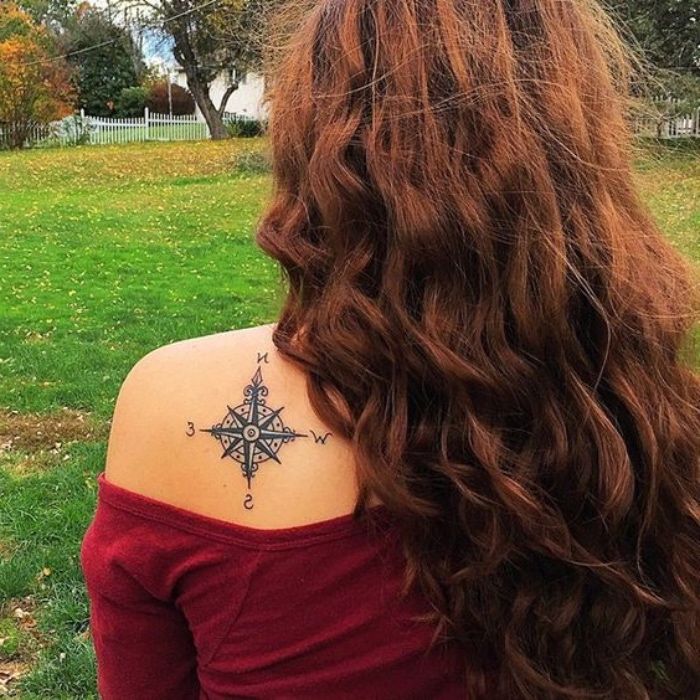 Mlada ženska z odlično tetovažo na njenem ramenskem delu - črna tetovaža s črnim kompasom