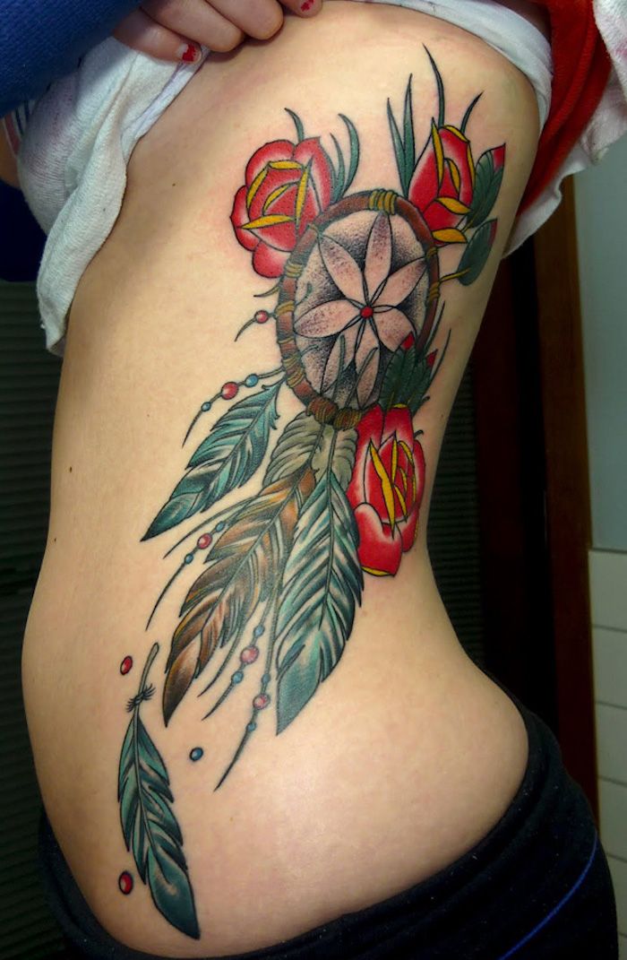 ecco un grande tatuaggio per una donna - un tatuaggio con un acchiappasogni e tre rose e foglie verdi