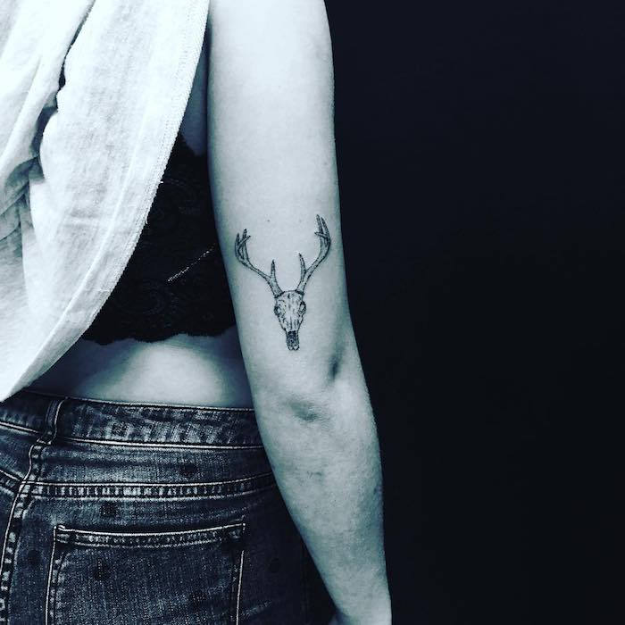 en kvinne med blå bukser - en hånd med en liten tatovering med en hvit hodeskalle og et hjort med lange horn
