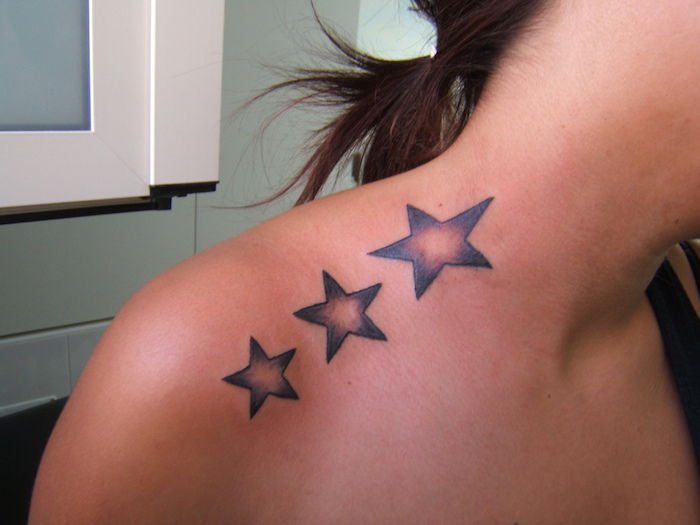 jonge vrouw met een zwarte ster tatoeage met drie grote sterren