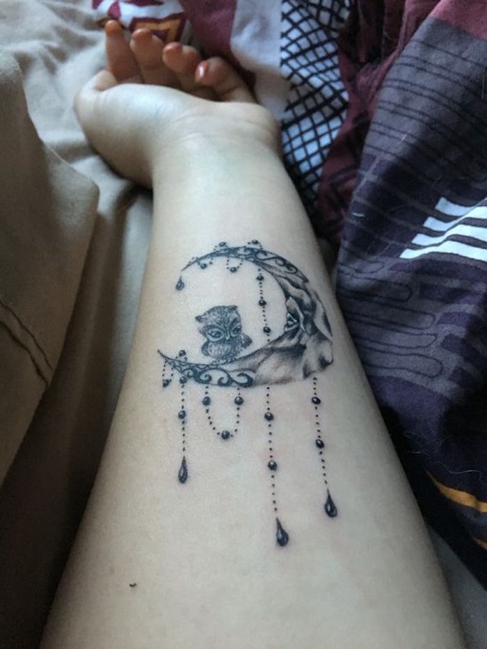 o lună neagră și o bufniță drăguță - idee pentru un tatuaj pe încheietura unei femei tinere