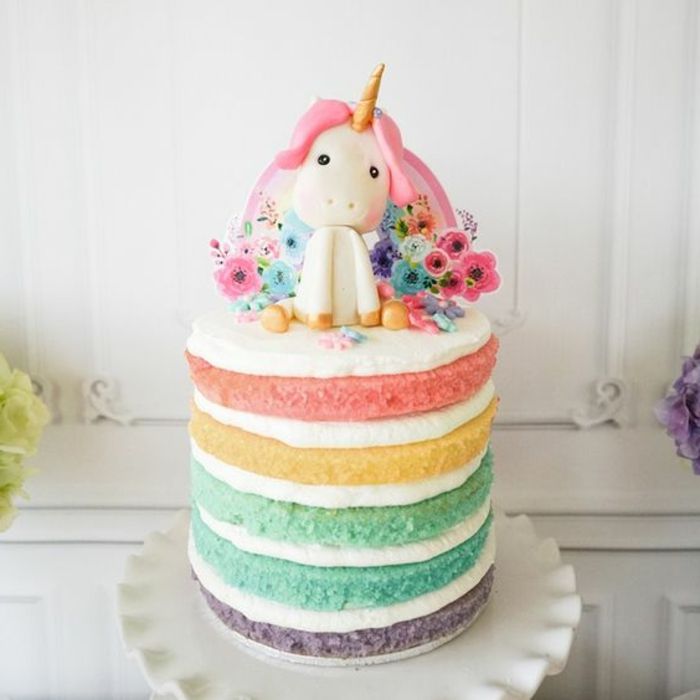 uma torta de unicórnio cor de arco-íris com flores