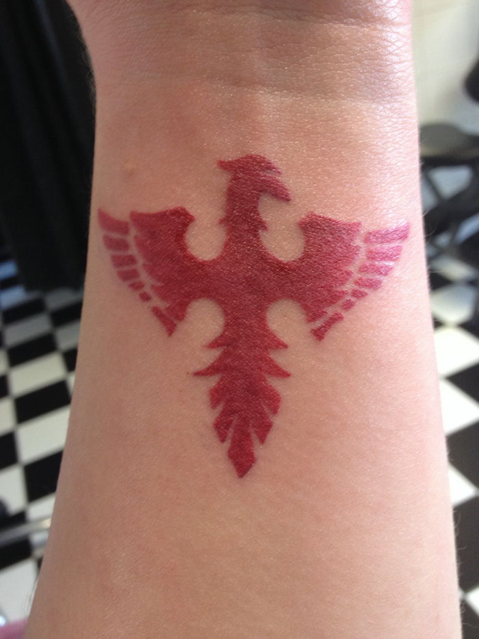 czerwony tatuaż z małym czerwonym feniksem z czerwonymi skrzydłami - tatuaż z feniksa na nadgarstku
