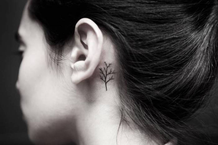 tattoo za ušesnimi motivi - mlada ženska z majhno črno tatoo za ušesom z majhno črno drevo